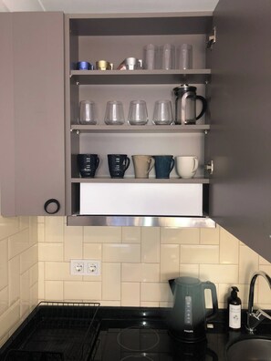 A kitchen with a built-in cabinet containing various glassware and a coffee maker. - Rich Area In Istanbul Suite 4 (Istanbul)