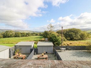 A view of a property with two small sheds, a wooden table, and a gravel area. - Holly (Cleator)