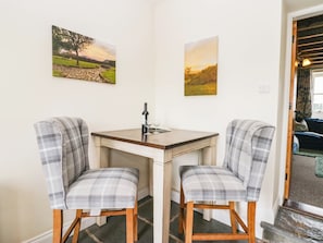 A corner room with two plaid chairs, a small table, and two paintings on the wall. - Acorn (Cleator)