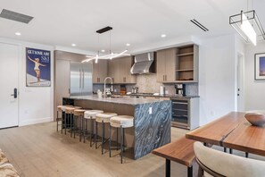 A modern kitchen with a central island, bar stools, and a dining table. - Frontgate 306 - 2 Bedroom + Office (Avon)