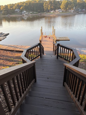 A wooden dock leading to a calm lake with a view of houses in the background. - The Landing at High Rock Lake-Lakefront-Private Dock-Sleeps 9 (Lexington)