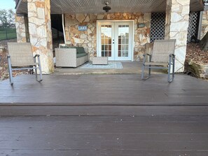 A covered patio with stone walls, a door with glass panels, and two rocking chairs. - The Landing at High Rock Lake-Lakefront-Private Dock-Sleeps 9 (Lexington)
