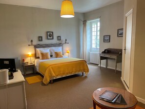 A hotel room with a bed, bedside lamps, a desk, a chair, a round table, and a window with curtains. - Christmas by the fireplace, elegant 18th-century home, sleeps 12, near St-Émilion (Ruch)