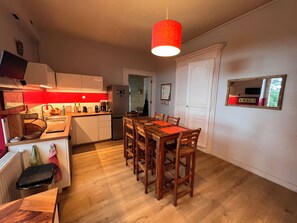 Een kleine keuken met een eethoek, houten meubels en een rode hanglamp.