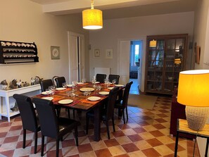Ruokailutilassa on ruutukuviollinen lattia, pitkä ruokapöytä, johon on katettu kuudelle, ja katosta roikkuva valaisin.