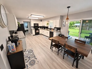 A modern kitchen with a dining area, a large window, and a view of the outdoors. - Game Room + Hot Tub Near Air Force Museum (Dayton)