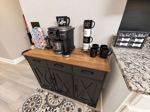 A kitchenette with a coffee maker, mugs, and a sign indicating dog walking services. - Game Room + Hot Tub Near Air Force Museum (Dayton)
