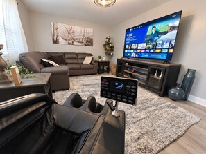 A living room with a leather sofa, a flat-screen TV, and a sound system. - Game Room + Hot Tub Near Air Force Museum (Dayton)