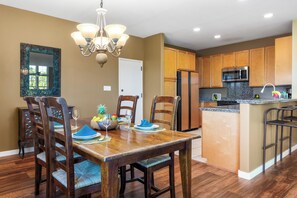 A dining area with a wooden table, chairs, and a chandelier. - Includes Hilton Pool Pass 2026!  1805 Waikoloa Colony Villas (Waikoloa Beach Resort)