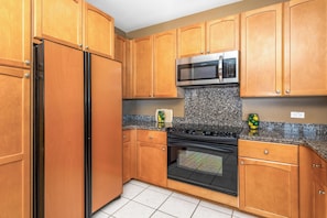 A kitchen with wooden cabinets, a stainless steel refrigerator, a microwave, and a stove. - Includes Hilton Pool Pass 2026!  1805 Waikoloa Colony Villas (Waikoloa Beach Resort)