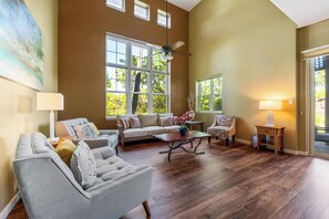 A spacious living room with a high ceiling, large windows, and a ceiling fan. - Includes Hilton Pool Pass 2026!  1805 Waikoloa Colony Villas (Waikoloa Beach Resort)