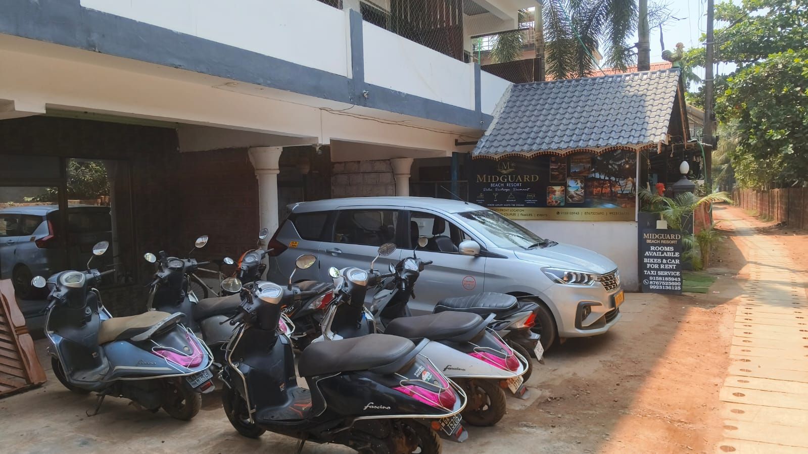Resort Midguard Beach con un estacionamiento que contiene varias motocicletas y un automóvil.