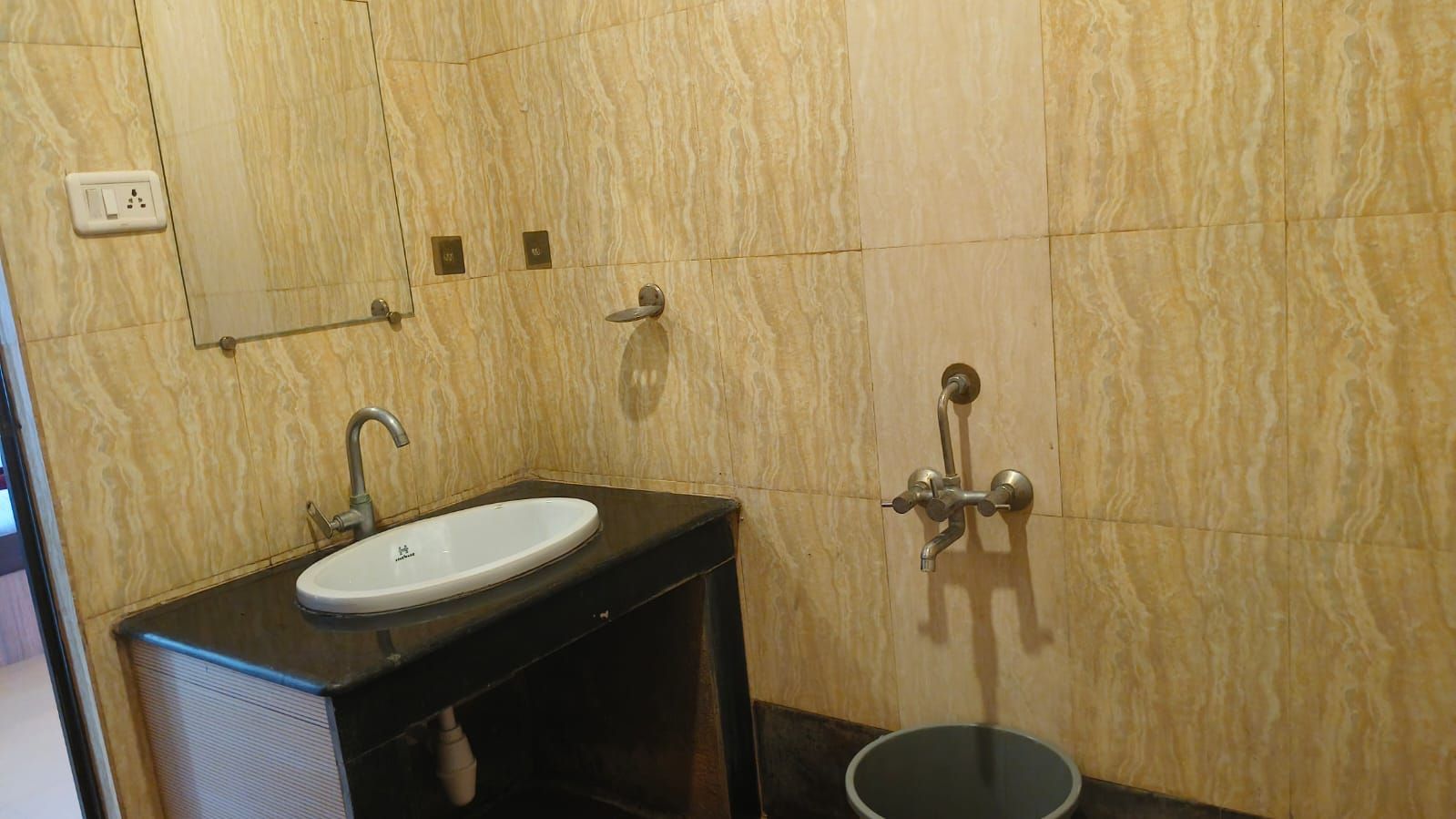 Casa de banho com lavatório, espelho e chuveiro.