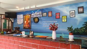Una recepción de hotel con una pared azul que muestra citas motivacionales y un reloj.