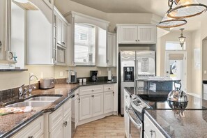 A modern kitchen with white cabinetry, granite countertops, stainless steel appliances, and a built-in oven. - Luxury Flagler Beach Home | Ocean Views | Private Swim Spa | Walk to Beach | 2 King Suites (Flagler Beach)