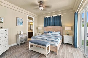 A bedroom with a bed, bedside tables, a bench, a dresser, a mirror, and a ceiling fan. - Luxury Flagler Beach Home | Ocean Views | Private Swim Spa | Walk to Beach | 2 King Suites (Flagler Beach)
