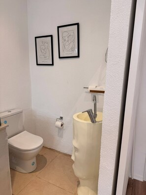 A bathroom with a toilet, sink, and two framed abstract artworks on the wall. - Rich Area In Istanbul Residence 4 (Istanbul)