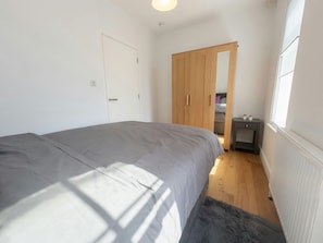 Ein Schlafzimmer mit Bett, Schrank, Heizkörper und Fenster.