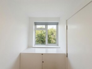 Ein Zimmer mit Fenster, weißer Wand und weißem Schrank.