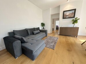 A modern living room with a grey sofa, a patterned rug, and a framed picture on the wall. - Stylish 2BR Home with Outdoor Dining/ Social Area (London)