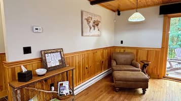 A wooden-floored room with a sofa, a small table with a globe and a framed menu, and a hanging light fixture.
