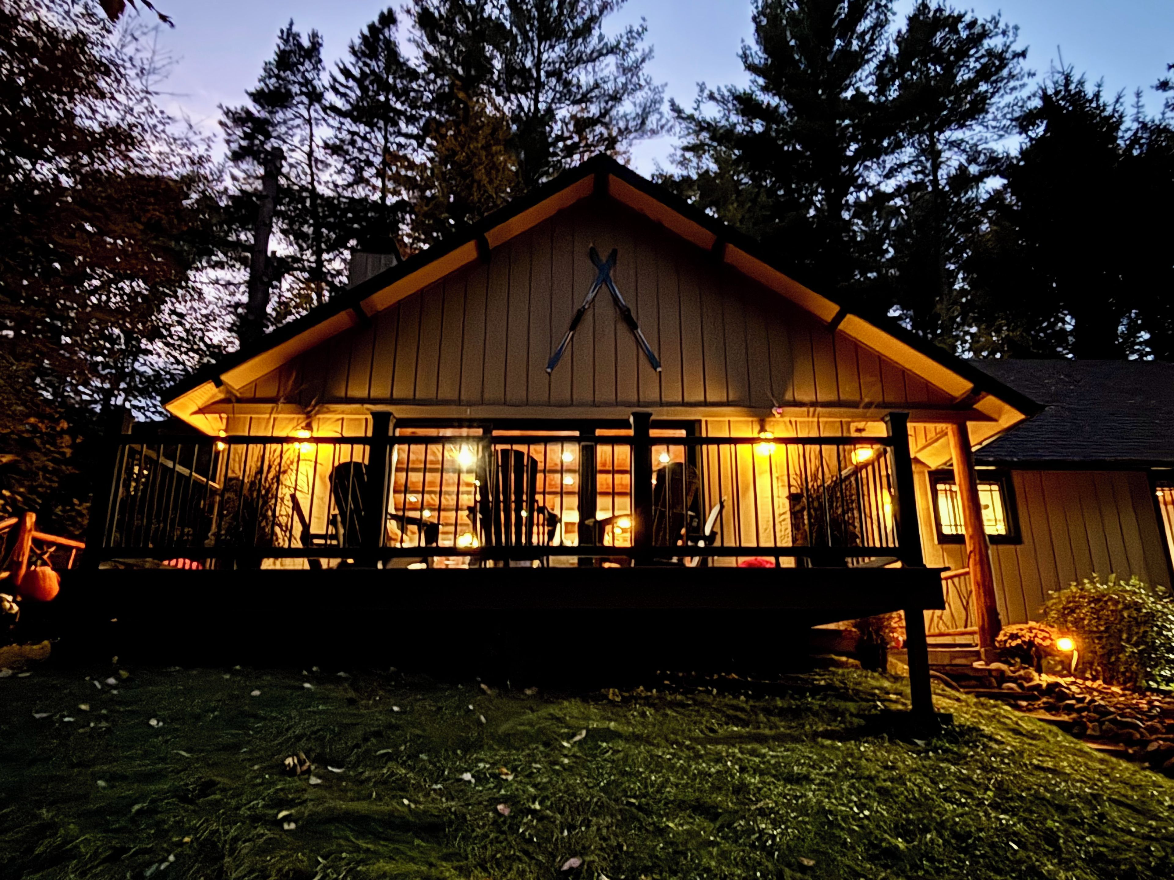 Une cabane en bois avec une véranda, une grande fenêtre et une cheminée.