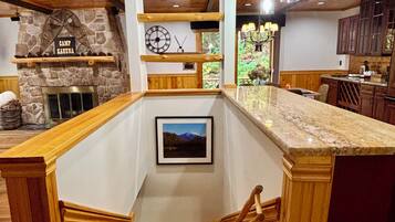 A wooden interior with a stone fireplace, a clock, and a framed picture on the wall.