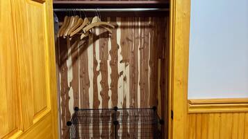 Un armario de madera con una barra para colgar y una cesta de alambre.