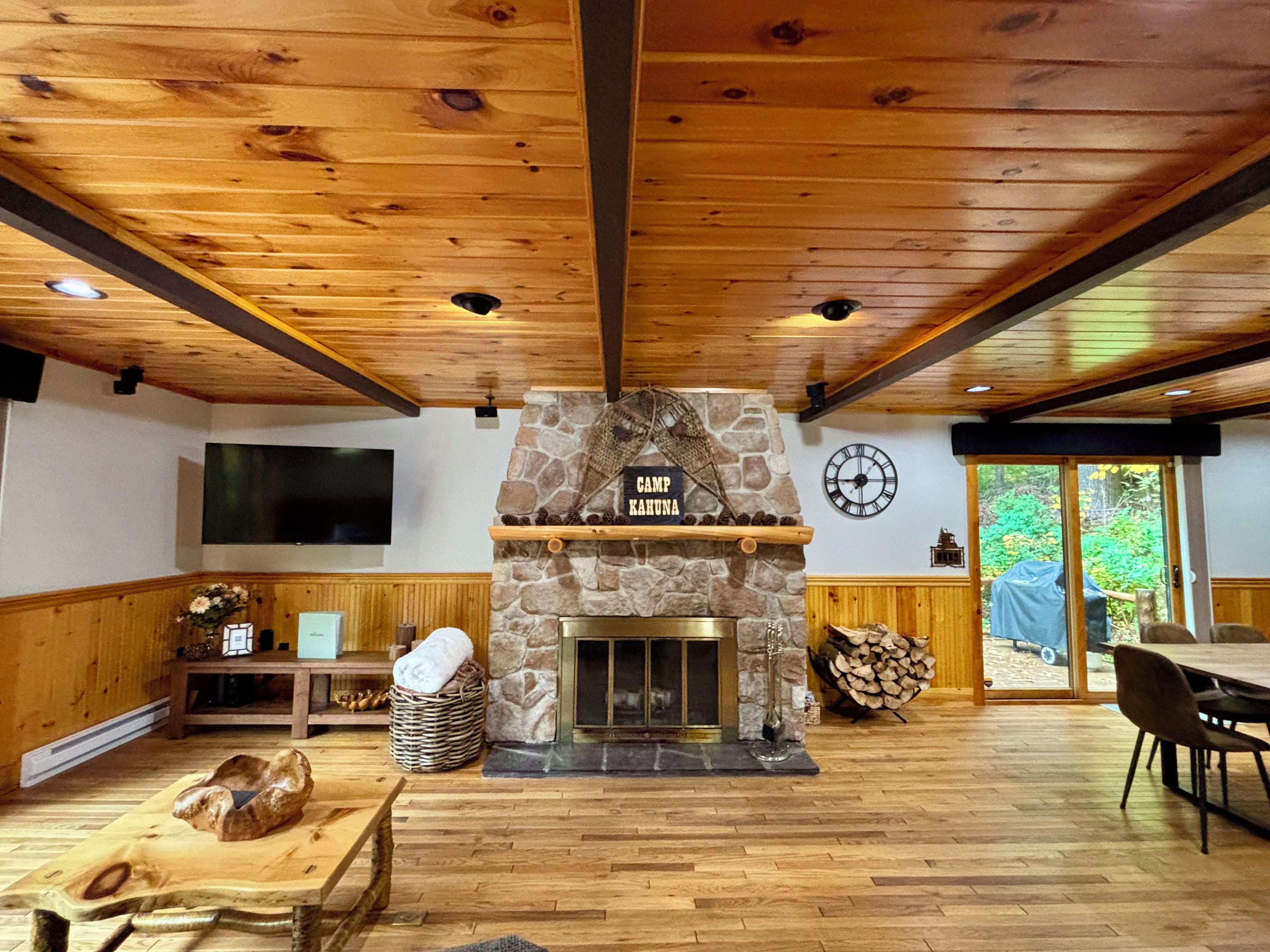 A cozy cabin interior with a stone fireplace, wooden flooring, and a dining area.