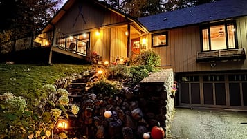 Una casa de dos pisos con un sendero de piedra que lleva a la puerta principal, rodeada de follaje otoñal y calabazas.