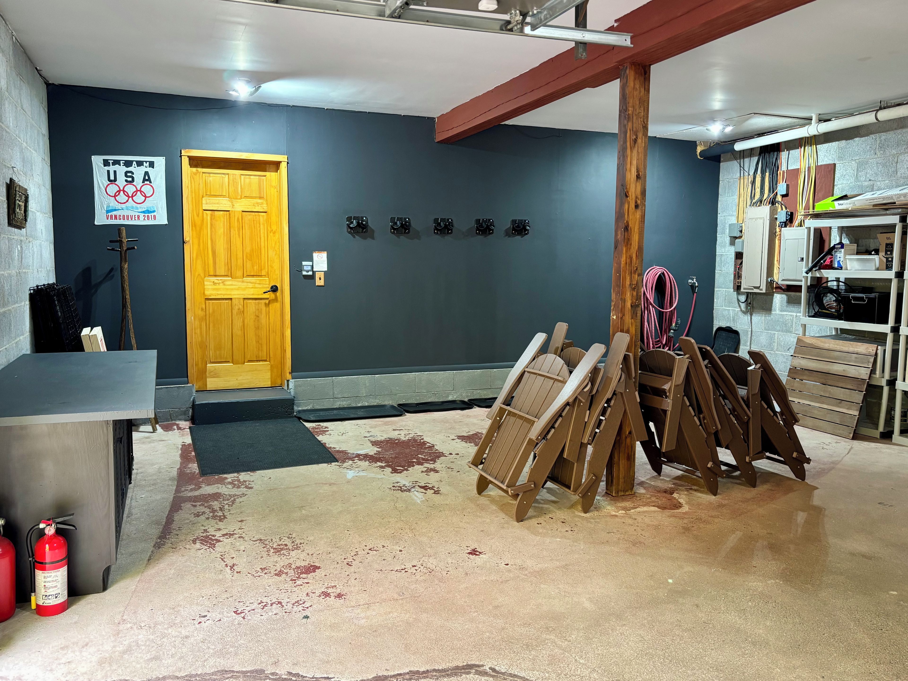 A room with a wooden door, a sign for Team USA at the Olympics, and several chairs.