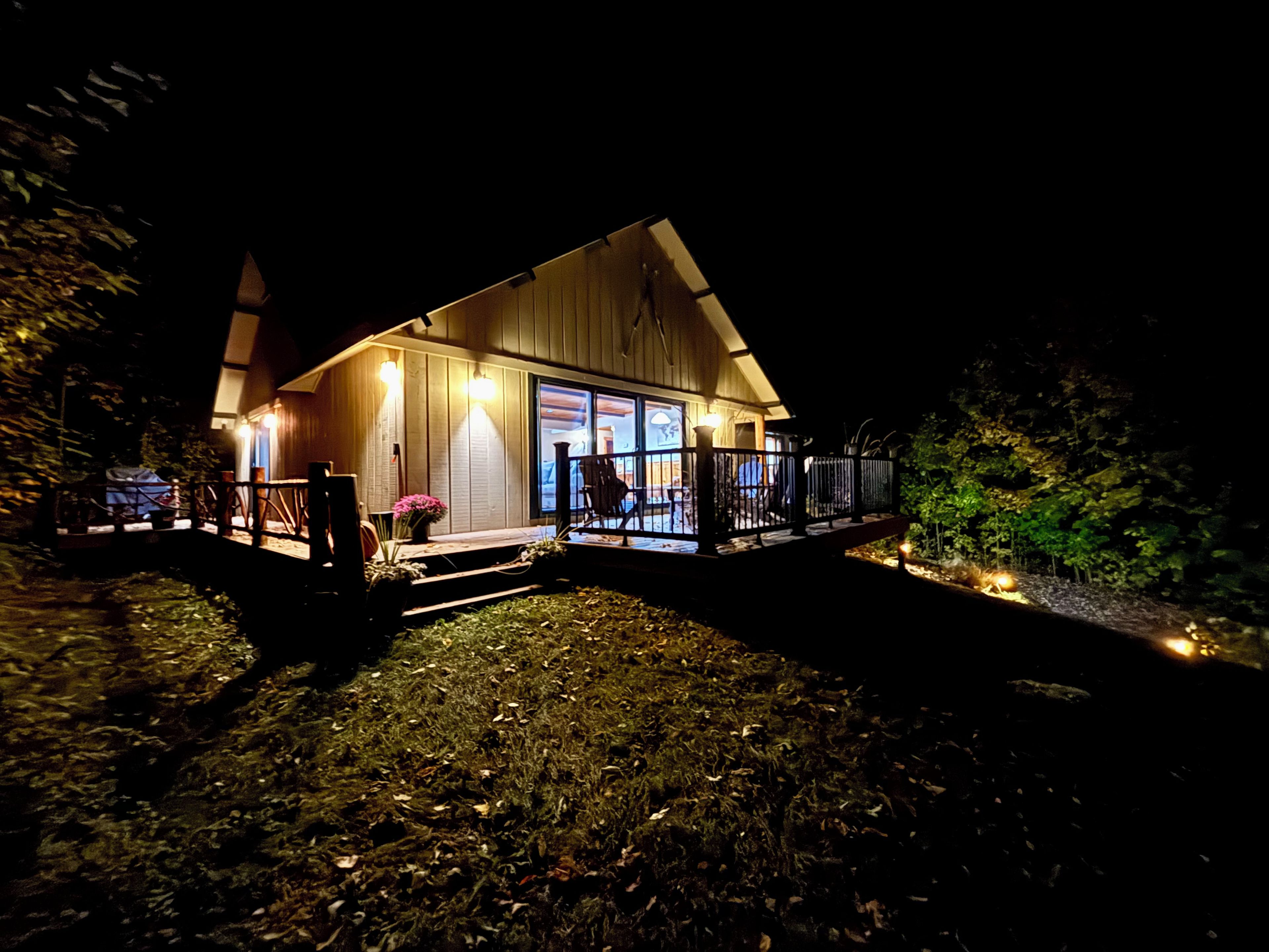 Uma cabana de madeira com varanda e deck, cercada por árvores.