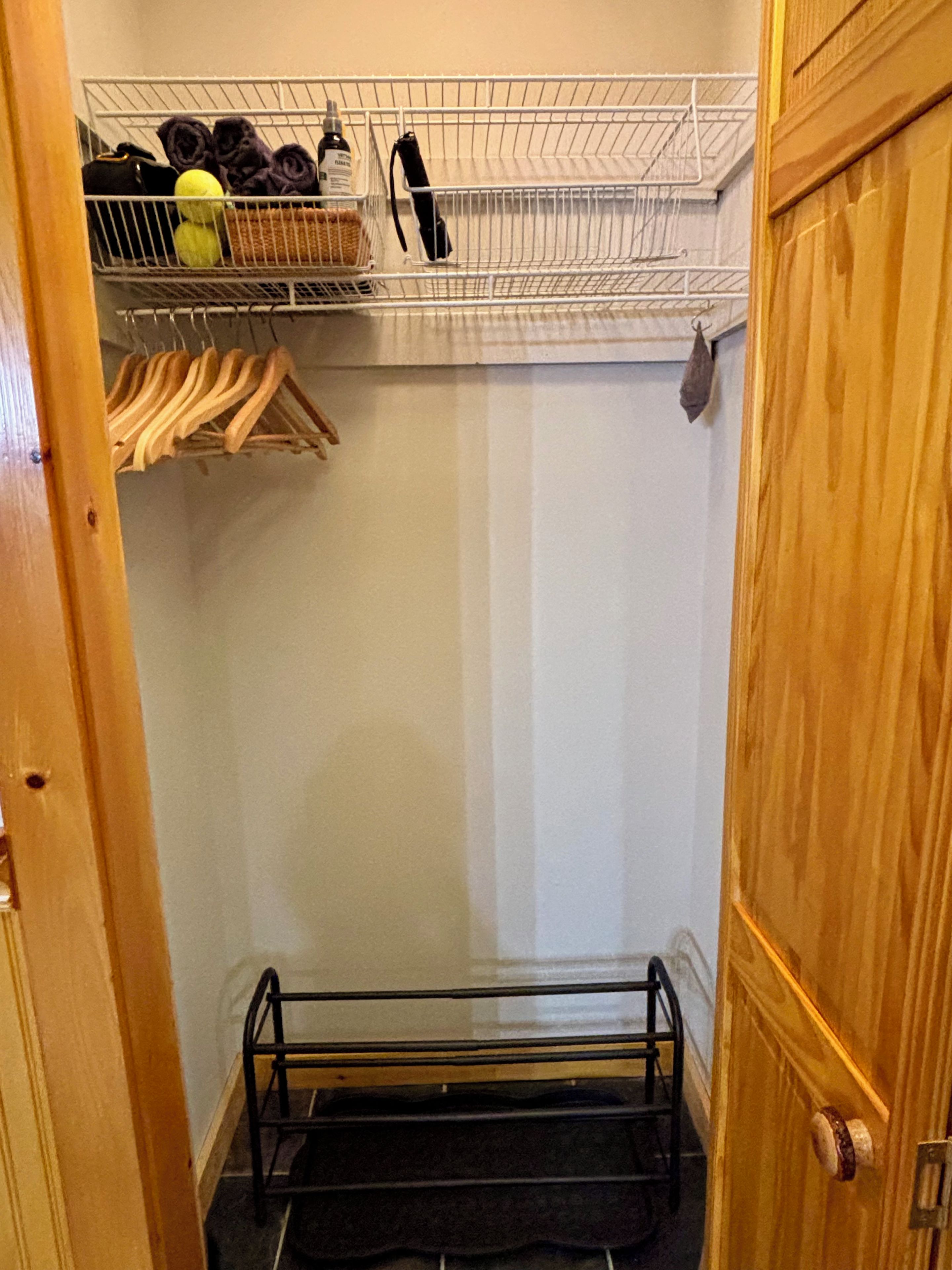 Un dressing avec une étagère en métal, des cintres en bois et un étendoir noir.