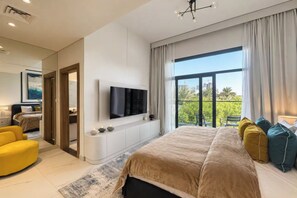 Een moderne slaapkamer met een groot bed, een flatscreen televisie aan de muur en een balkon met uitzicht over de stad.