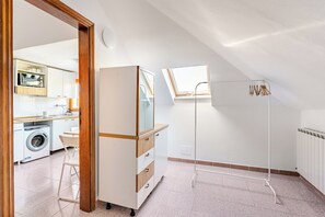 Een compacte kamer met een kitchenette, een ingebouwde wasmachine en een kleine eethoek.