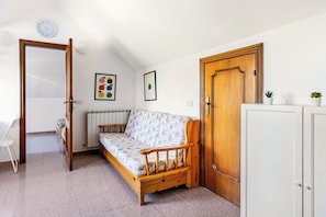 Een kleine, knusse kamer met een enkel bed, een radiator, een houten deur en een witte kast.
