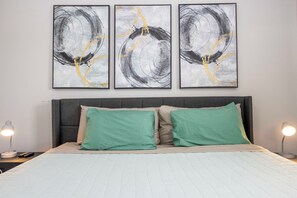 A bedroom with a bed, two green pillows, a grey headboard, and three abstract paintings on the wall. - Prime Location Bella Vida Pool Retreat Near Disney (Kissimmee)