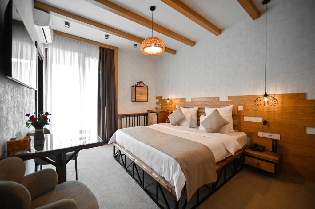 Quarto com cama, mesas de cabeceira, escrivaninha e uma cadeira.
