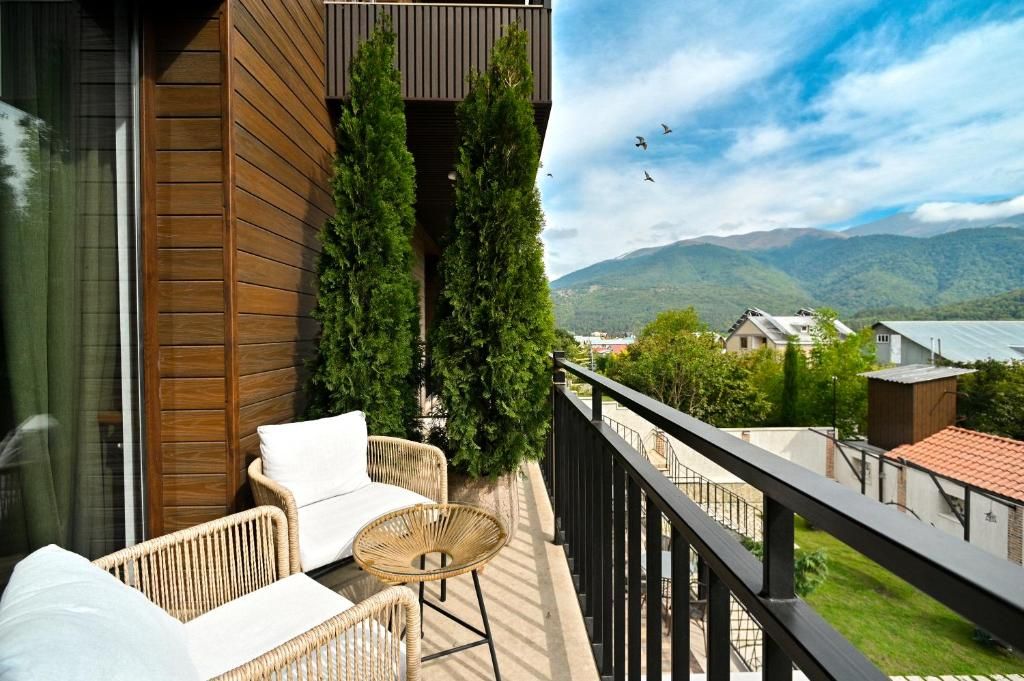 A balcony with wicker furniture, a view of mountains, and a clear sky.