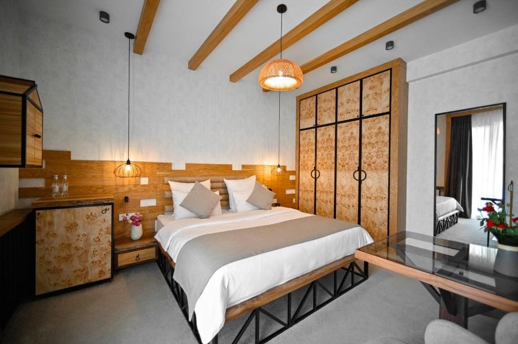 Un dormitorio moderno con cabecera de madera, una mesita de vidrio y un espejo grande.