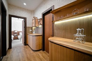 A wooden interior with a reception desk, a coffee machine, and a shelf with glasses.