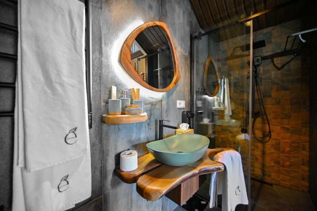 Un baño con tocador de madera, lavabo y espejo con marco de madera.