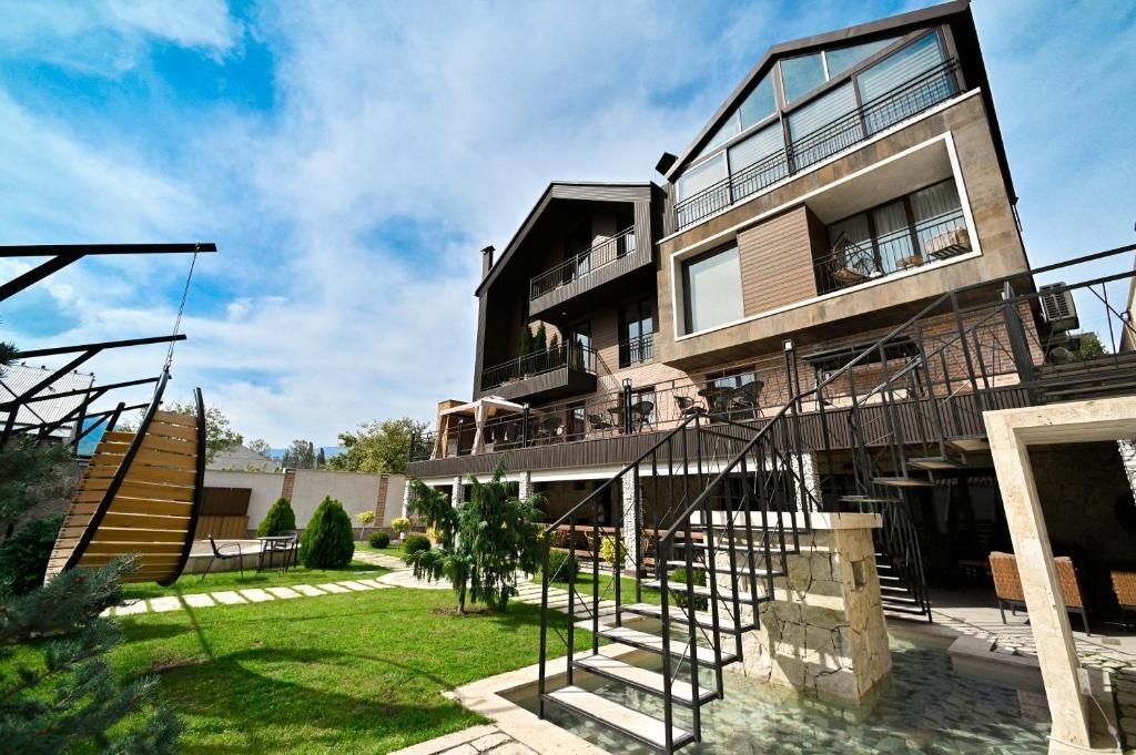 Um edifício moderno de vários andares com uma área externa ampla, incluindo uma escadaria e uma piscina.