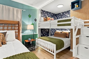 A bunk bed with a green blanket, a bedside table with a lamp, and a wall with a floral pattern. - Windsor Hills 6BR Disney Home with Themed Rooms (Kissimmee)