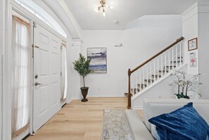 A hallway with a staircase, a potted plant, and a painting on the wall. - 6BR Windsor Hills Home Near Disney with Pool (Kissimmee)