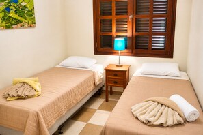 A hotel room with two beds, a nightstand, a lamp, and a window with blinds. - Poco Poco Villa at Blue Bay Resort | Pool, Beach & Golf (Willemstad)