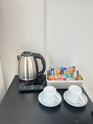A kitchenette with a kettle, a basket of snacks, and two cups on a table. - THE PARADISE INN PATTAYA (Muang Pattaya)