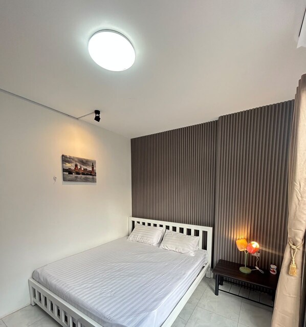 A modern bedroom with a bed, a bedside lamp, a picture on the wall, and a ceiling light. - THE PARADISE INN PATTAYA (Muang Pattaya)