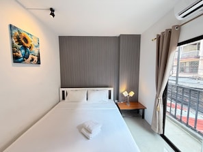 Habitación de hotel con cama, un cuadro, una ventana con cortinas y un equipo de aire acondicionado.