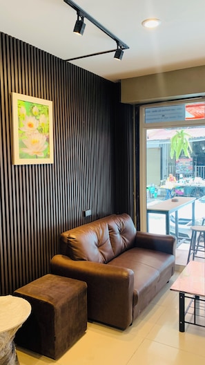 A modern interior with a leather sofa, a small ottoman, and a table. - THE PARADISE INN PATTAYA (Muang Pattaya)
